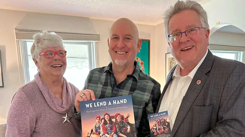 Senator Rob Black, Colin Field and Bonnie Sitter hold We Lend a Hand's poster